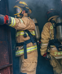 Two firefighters enter a smokey doorway