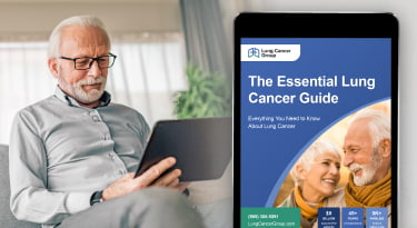 A man sits holding a tablet with a closeup of the Essential Lung Cancer Guide shown on the tablet